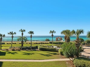 Blick auf einen Strand mit Palmen, einer Laube und wolkenlosem, blauem Himmel.