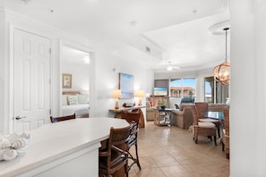 A spacious living area with a dining table, chairs, a sofa, and a kitchen area. - Gorgeous Top Floor Condo at Mediterranea (Miramar Beach)