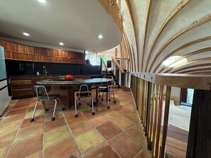A modern kitchen with a curved island, wooden cabinets, and a view of the outdoors. - Oscar winning living @ Livingstations (Woodstock)