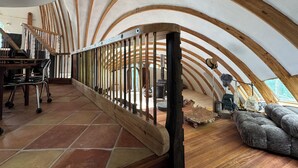 A spacious, high-ceilinged interior with a wooden staircase, a seating area, and a visible fireplace. - Oscar winning living @ Livingstations (Woodstock)