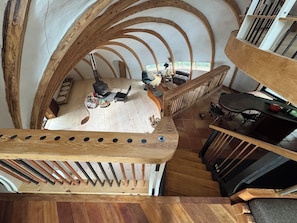 A high-ceilinged room with exposed wooden beams, a fireplace, and a staircase. - Oscar winning living @ Livingstations (Woodstock)