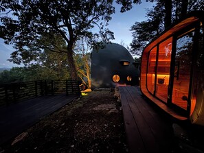 A unique geodesic dome house with a wooden deck and glass windows.