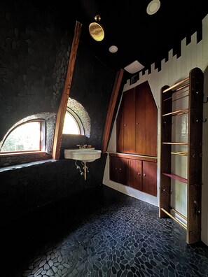 A rustic bathroom with a stone wall, a wooden door, a window, and a sink. - Oscar winning living @ Livingstations (Woodstock)