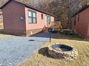 A log cabin with a stone fire pit and a picnic table. - Cozy 2-Bedroom Cabin Near Two Kings Casino & Local Attractions (Grover)