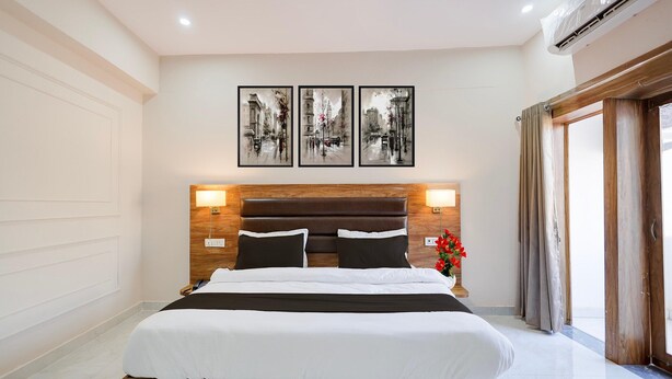 A hotel room with a large bed, wooden headboard, and three framed pictures on the wall. - Deluxe With Balcony Haldwani inn 2.0 (Haldwani)