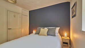 A bedroom with a bed, bedside lamps, a wardrobe, and a framed picture on the wall. - Host & Stay | Lower Cross Lee Cottage (Todmorden)