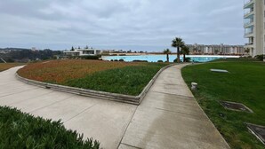 A resort with a pool, a walking path, and a view of the ocean. - Oceana Suites Laguna Bahía (Algarrobo)