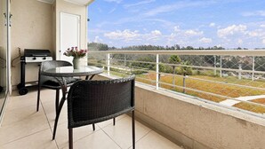 A balcony with a grill, wicker furniture, and a view of the countryside. - Oceana Suites Laguna Bahía (Algarrobo)