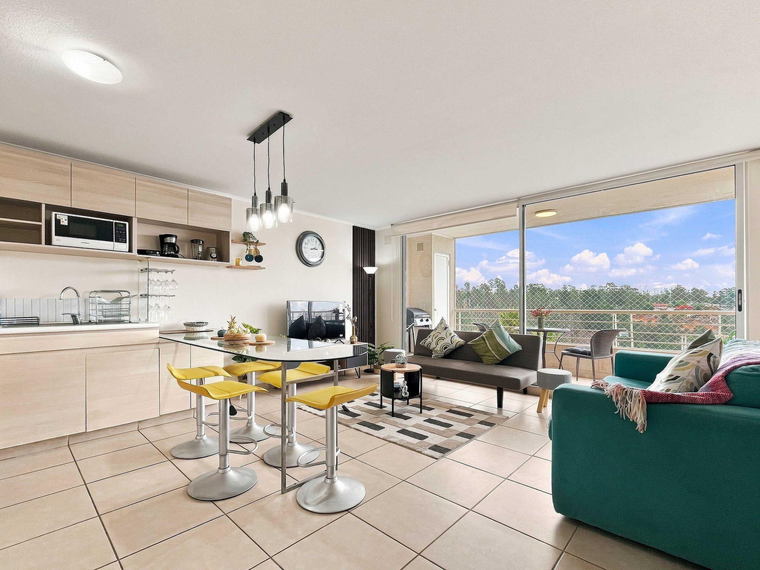 A modern apartment with a kitchen, dining area, and a balcony with a city view.