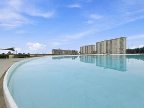 Une piscine dont l’eau reflète clairement les bâtiments qui se trouvent à l’arrière-plan.