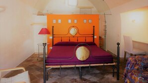 A room with a bed, a chair, a lamp, and a wall with pictures. - Casa della Luna (Matera)