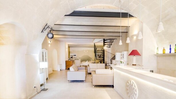 A modern interior with a central staircase, white furniture, and a reception area. - Casa della Luna (Matera)