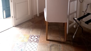 A room with a white door, a white chair, a small table, a kettle, and a wall-mounted air conditioner. - Casa della Luna (Matera)