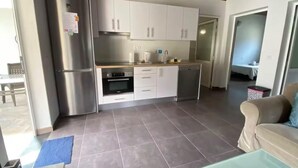 A modern kitchen with stainless steel appliances, white cabinets, and a tiled floor. - Finca House by Fataga Maspalomas (San Bartolomé de Tirajana)