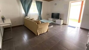 A living room with a sofa, a TV, and a window with curtains. - Finca House by Fataga Maspalomas (San Bartolomé de Tirajana)