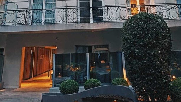 Ein Gebäude mit Balkon, Treppe und einem großen Baum davor.
