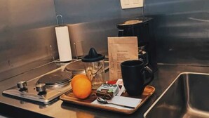 Eine Küchenarbeitsplatte mit einer Kaffeemaschine, einer Tasse, einer Schale mit einer Banane, einer Flasche und einer Papiertüte.