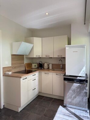 Eine kompakte Küche mit integriertem Kühlschrank, einer Spüle und einer Arbeitsplatte mit Wasserkocher und Toaster.