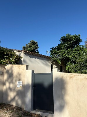 A gated entrance with a closed door, a security camera, and a small window above the door. - Air-conditioned detached house with a garden—5 minutes from Avignon (Villeneuve-lès-Avignon)
