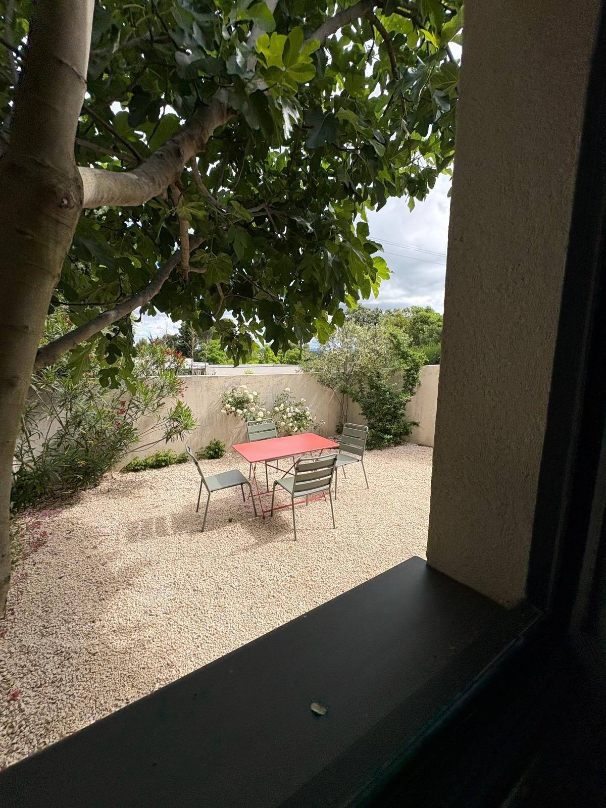 A patio with a table and chairs, surrounded by gravel and plants.