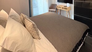 Una camera da letto moderna con un letto, una scrivania con un televisore e una sedia.