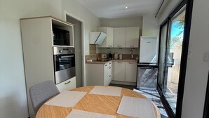 Cucina compatta con elettrodomestici moderni, zona pranzo con tavolo rotondo e vista attraverso un'ampia finestra.