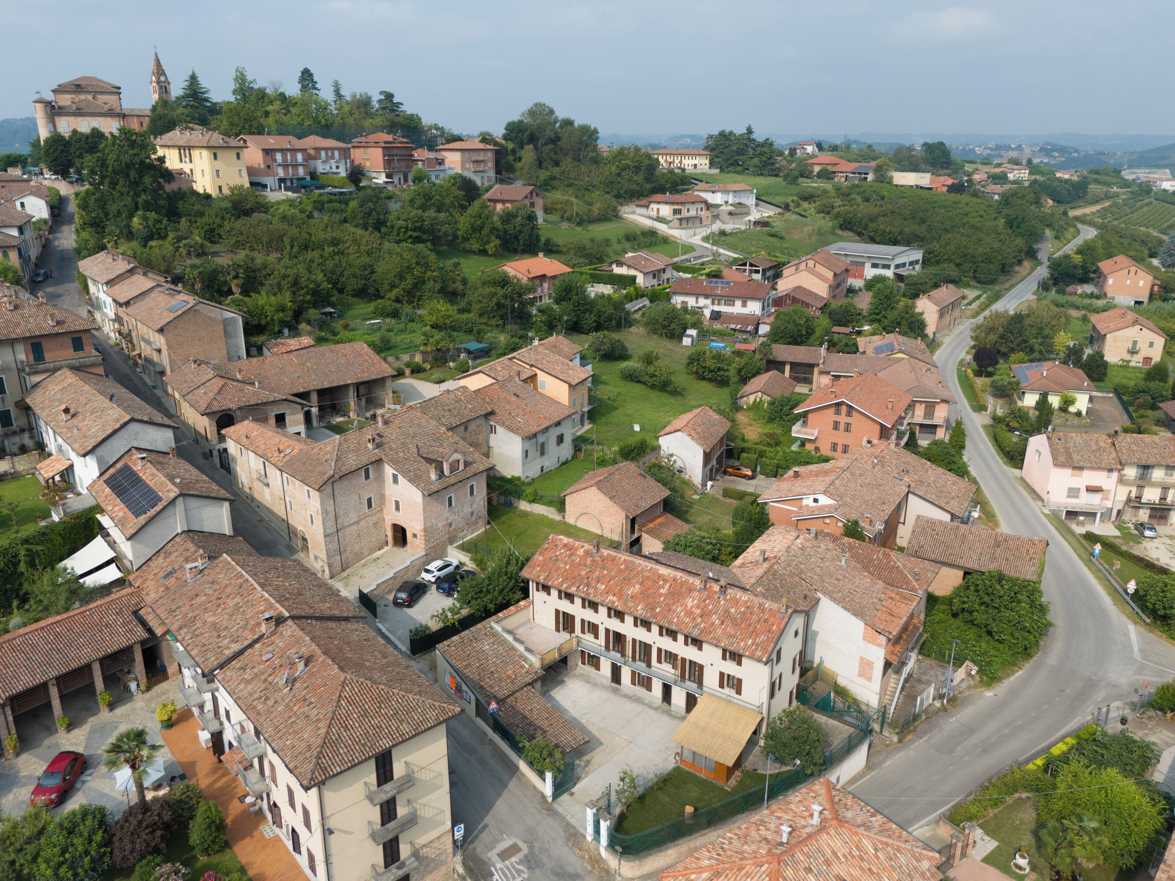 Un quartier résidentiel avec des maisons aux toits de tuiles, une église dotée d’un clocher et une route sinueuse.