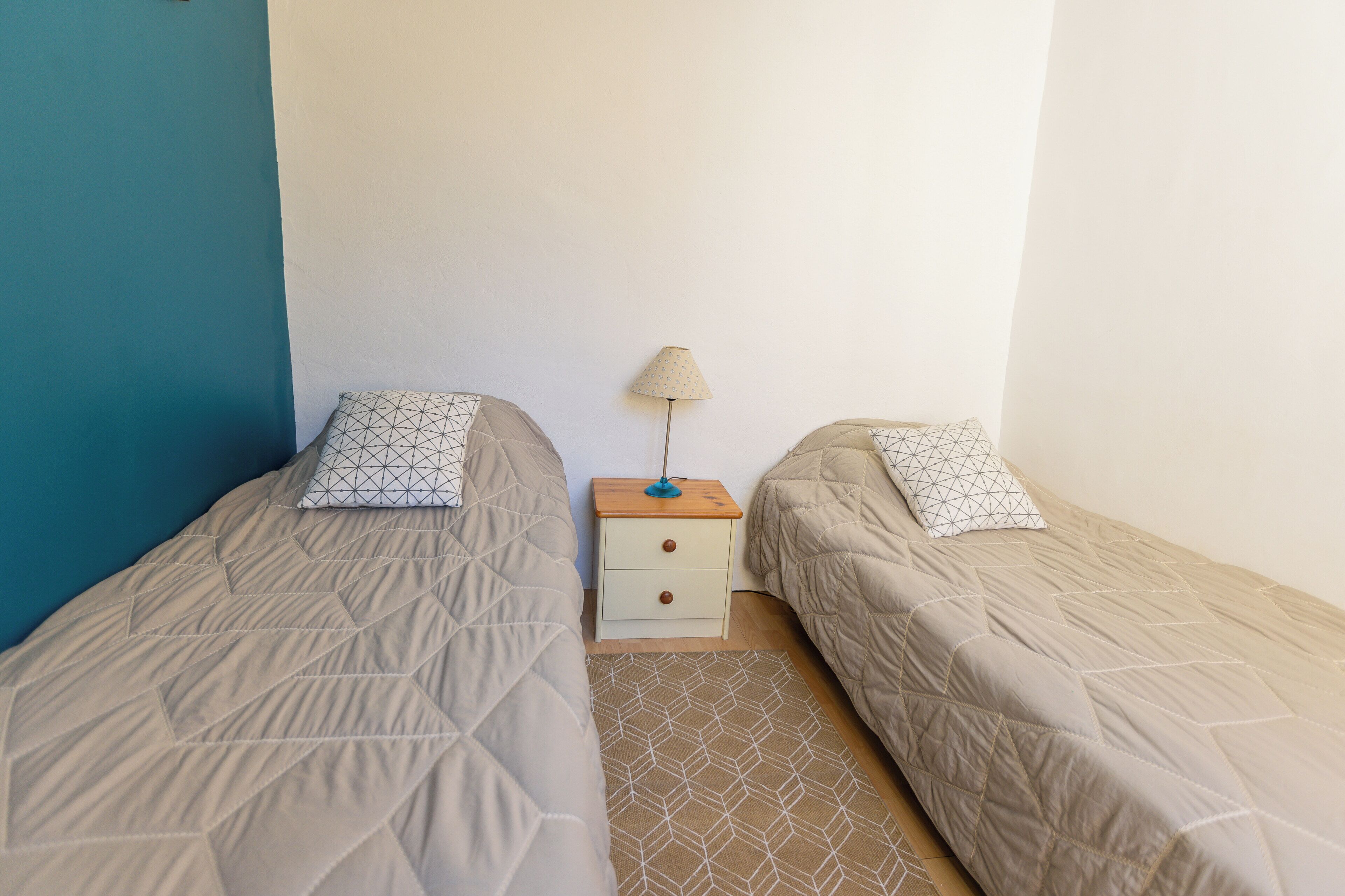 A twin room with two beds, a nightstand, and a lamp.