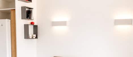 A modern hotel room with a large bed, a built-in wardrobe, bedside tables, and wall-mounted light fixtures.