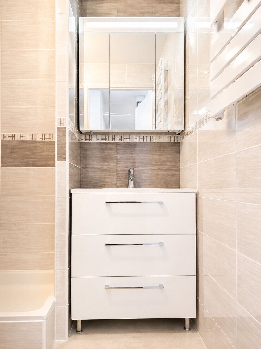 A modern bathroom with a white vanity, a mirror, and a tiled backsplash.