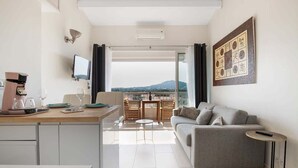 A modern room with a sofa, a small table, a TV, and a balcony with a view. - Naturiste Cap d'Agde Port Soleil 590 (Cap d'Agde)
