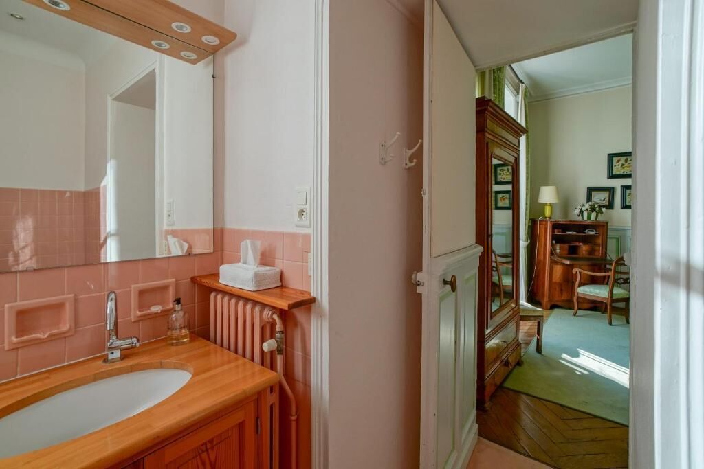 Een badkamer met een houten wastafelmeubel, een grote spiegel en een radiator.