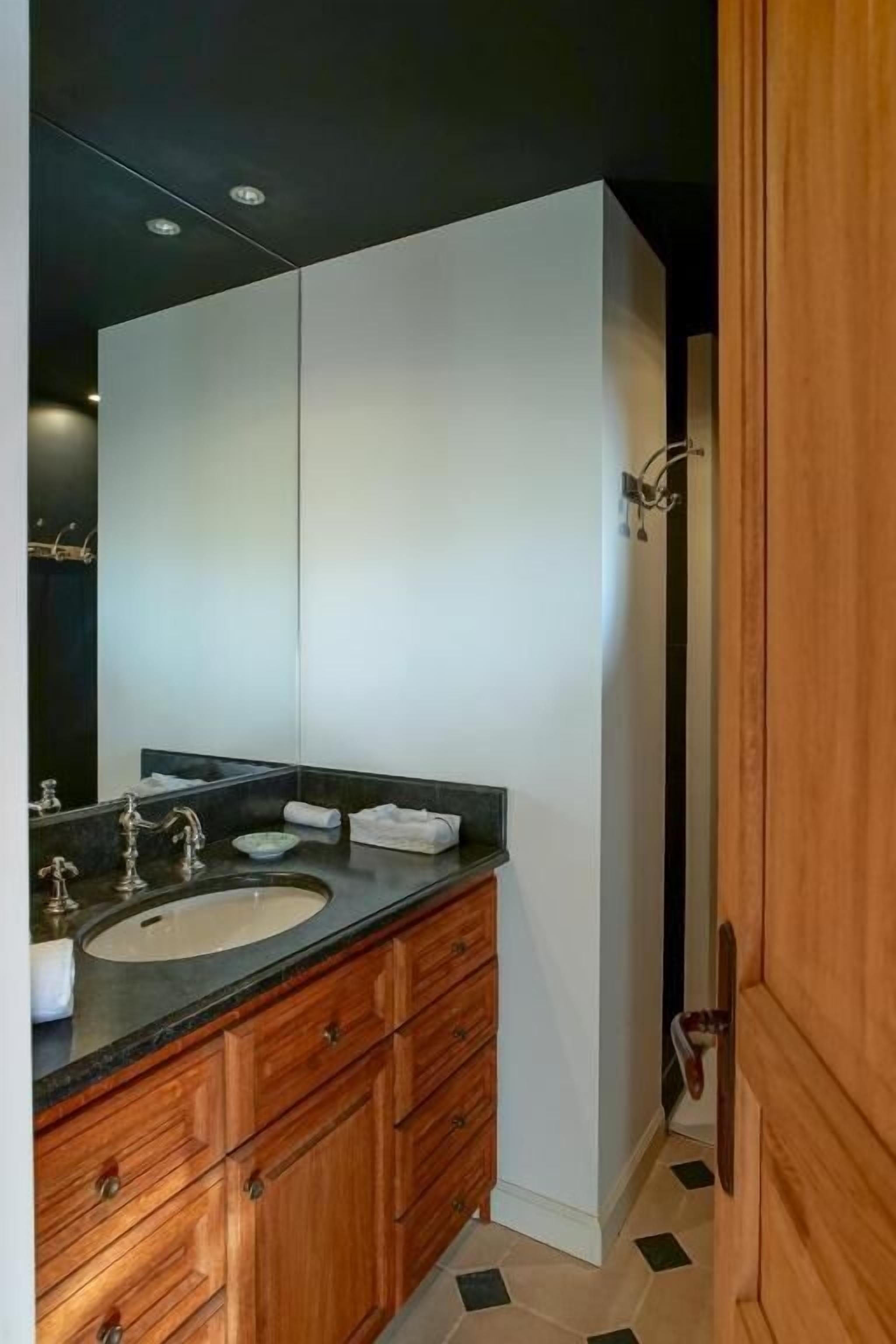 Une salle de bain moderne avec un meuble-lavabo à deux vasques, un grand miroir et une porte en bois.