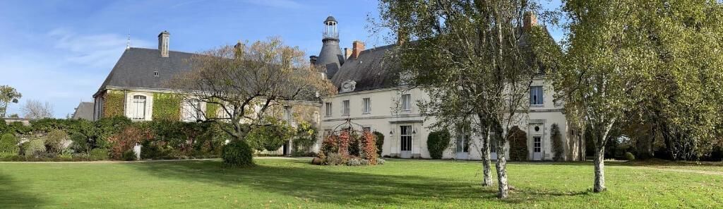 Un grand bâtiment historique, doté d’une tour imposante, entouré d’un jardin bien entretenu.