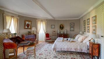 A bedroom with a bed, a desk, a chair, a dresser, and a red armchair.