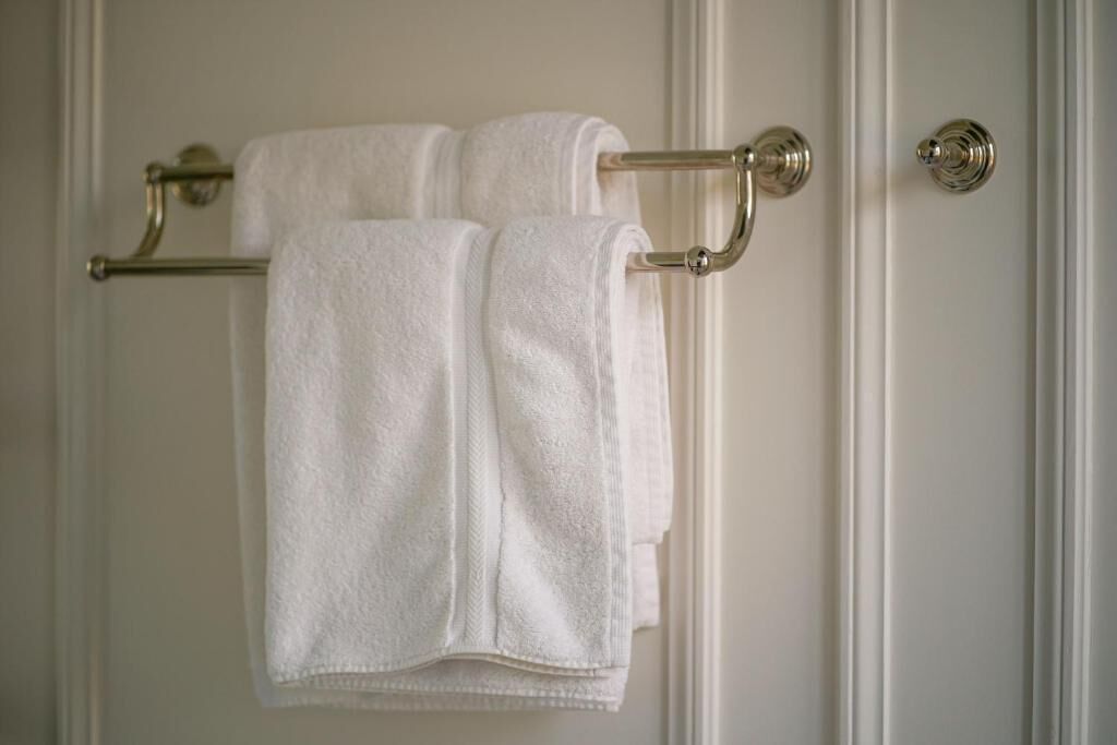A white door with a towel rack holding two white towels.