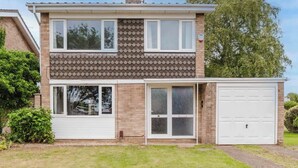 En toetages boligbygning med garage, hoveddør og en lille forhave.