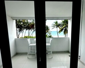 A balcony with two white chairs, a view of the ocean, and palm trees. - Palmas Terrace Studio Breathtaking Ocean View (San Juan)