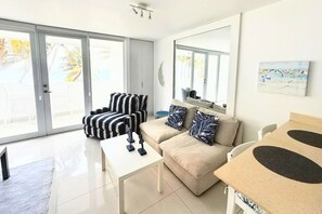 A modern living room with a sofa, armchair, coffee table, and a dining area. - Palmas Terrace Studio Breathtaking Ocean View (San Juan)