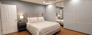 A bedroom with a bed, nightstand, lamp, and a wardrobe. - Houston Bungalow Near Sports, Downtown & Parks! (Houston)