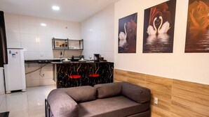 A modern kitchen with white tiles, a built-in microwave, and a dining area with a black marble countertop. - Comfort and tranquility near the airport (Vitória)