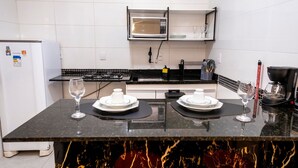 A kitchen with a microwave, stove, and two wine glasses on the counter. - Comfort and tranquility near the airport (Vitória)