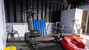 A gym with exercise equipment, a red bean bag, and a chair. - Modern and functional studio apartment near Garoto (Vila Velha)
