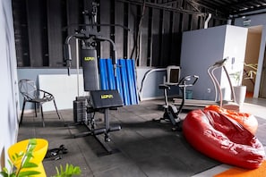 Ein Fitnessraum mit Trainingsger äten, einem roten Sitzsack und einem Stuhl.