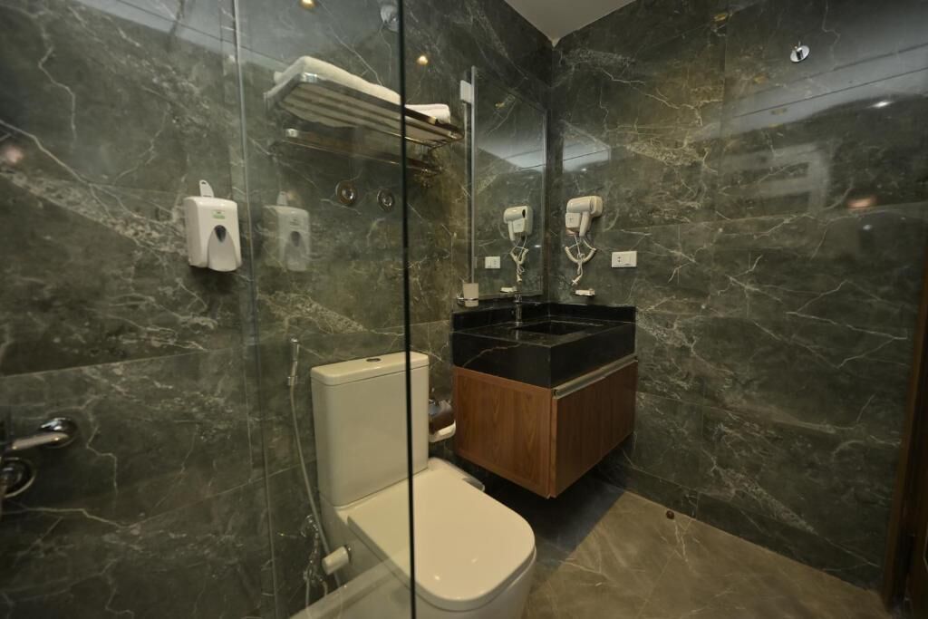 A bathroom with a glass-enclosed shower, a toilet, and a vanity with a black countertop.