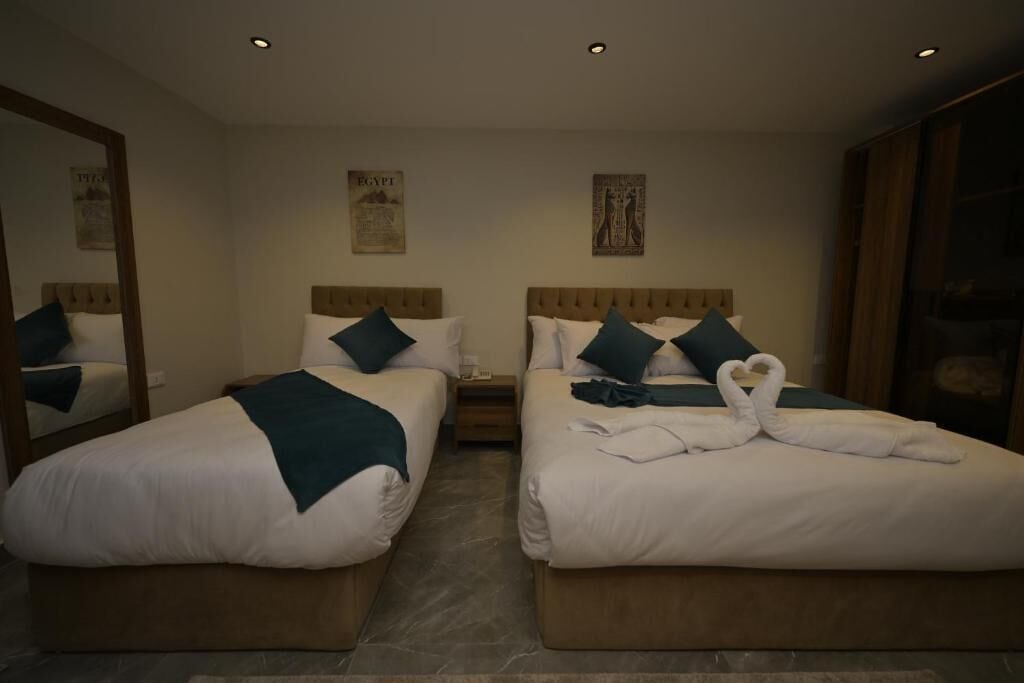 Habitación de hotel con dos camas, un espejo grande y obras de arte en las paredes.