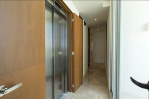 A corridor with sliding doors and a glass partition, leading to a room with a door.