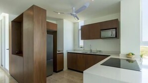 A modern kitchen with wooden cabinets, a built-in microwave, and a central island. - Beachfront Paradise with Shared Pool Telchac | Depto A12 (Telchac Puerto)