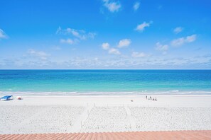 A beach with a clear sky, calm sea, and a white sandy shore.