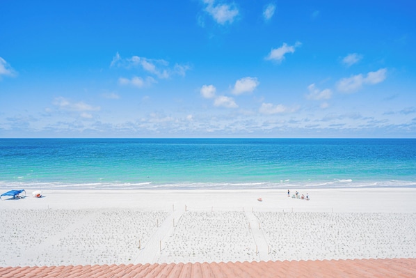 Une plage avec un ciel dégagé, une mer calme et un rivage de sable blanc.